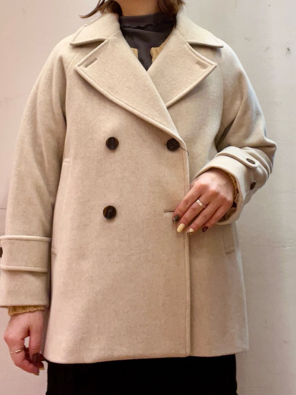 ベージュ系のピーコート、ベージュ系のトップス、ブラウン系のブーツを着用したレディースの冬コーディネートの4枚目の写真