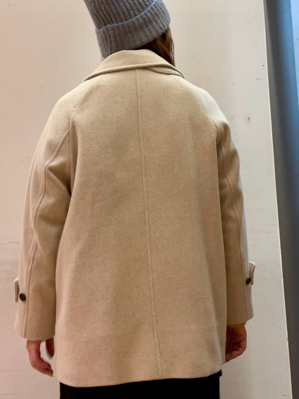 ベージュ系のピーコート、ベージュ系のトップス、ブラウン系のブーツを着用したレディースの冬コーディネートの5枚目の写真