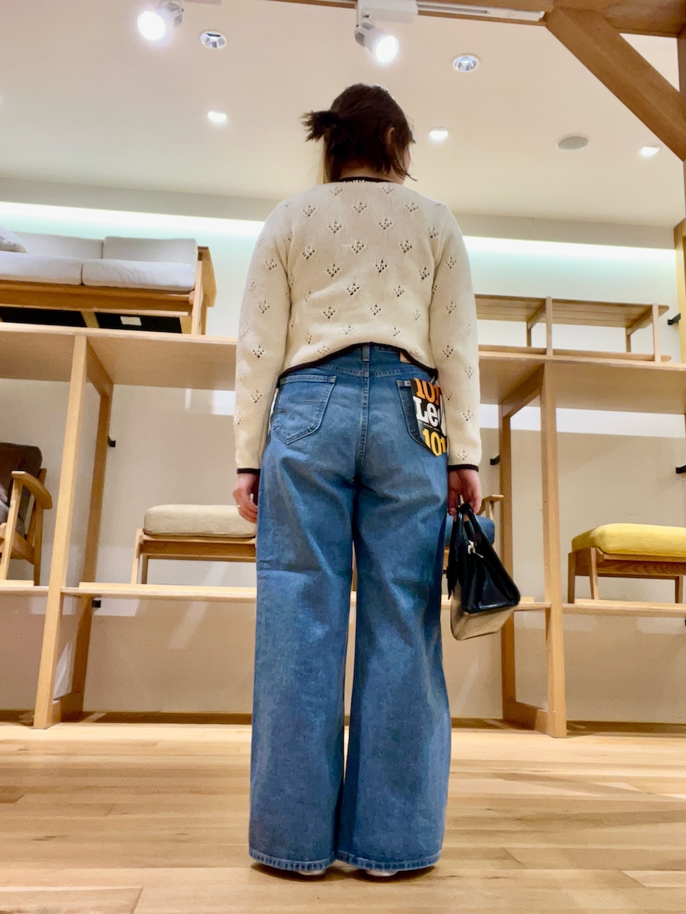 ブラック系のボストンバッグ、ベージュ系のタンクトップ、ブルー系のデニムパンツを着用したレディースの冬コーディネートの3枚目の写真