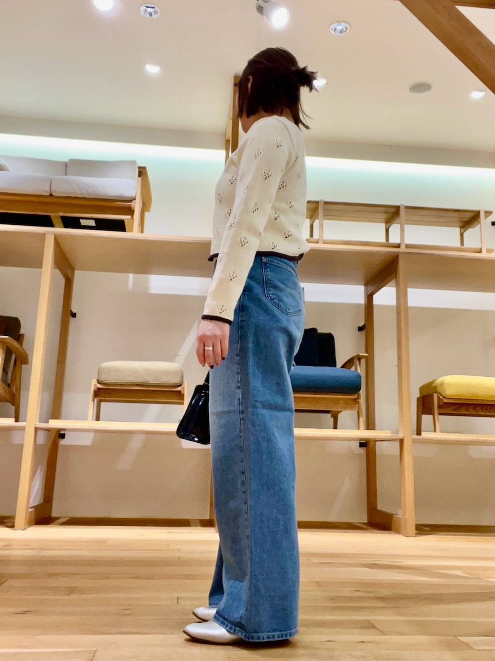 ブラック系のボストンバッグ、ベージュ系のタンクトップ、ブルー系のデニムパンツを着用したレディースの冬コーディネートの2枚目の写真