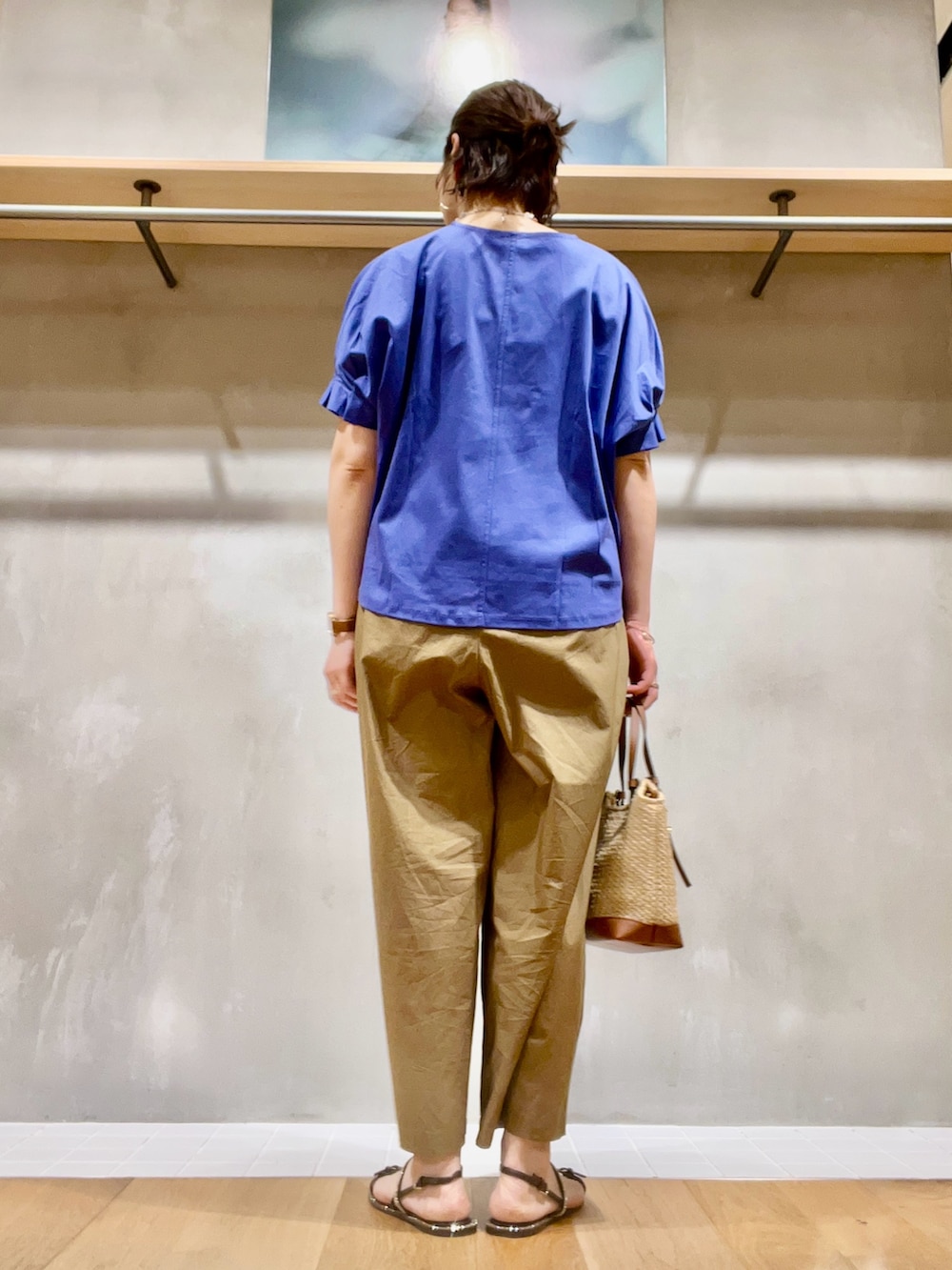 ブルー系のTシャツ/カットソー、ブラウン系のパンツ、ベージュ系のかごバッグを着用したレディースの夏コーディネートの4枚目の写真