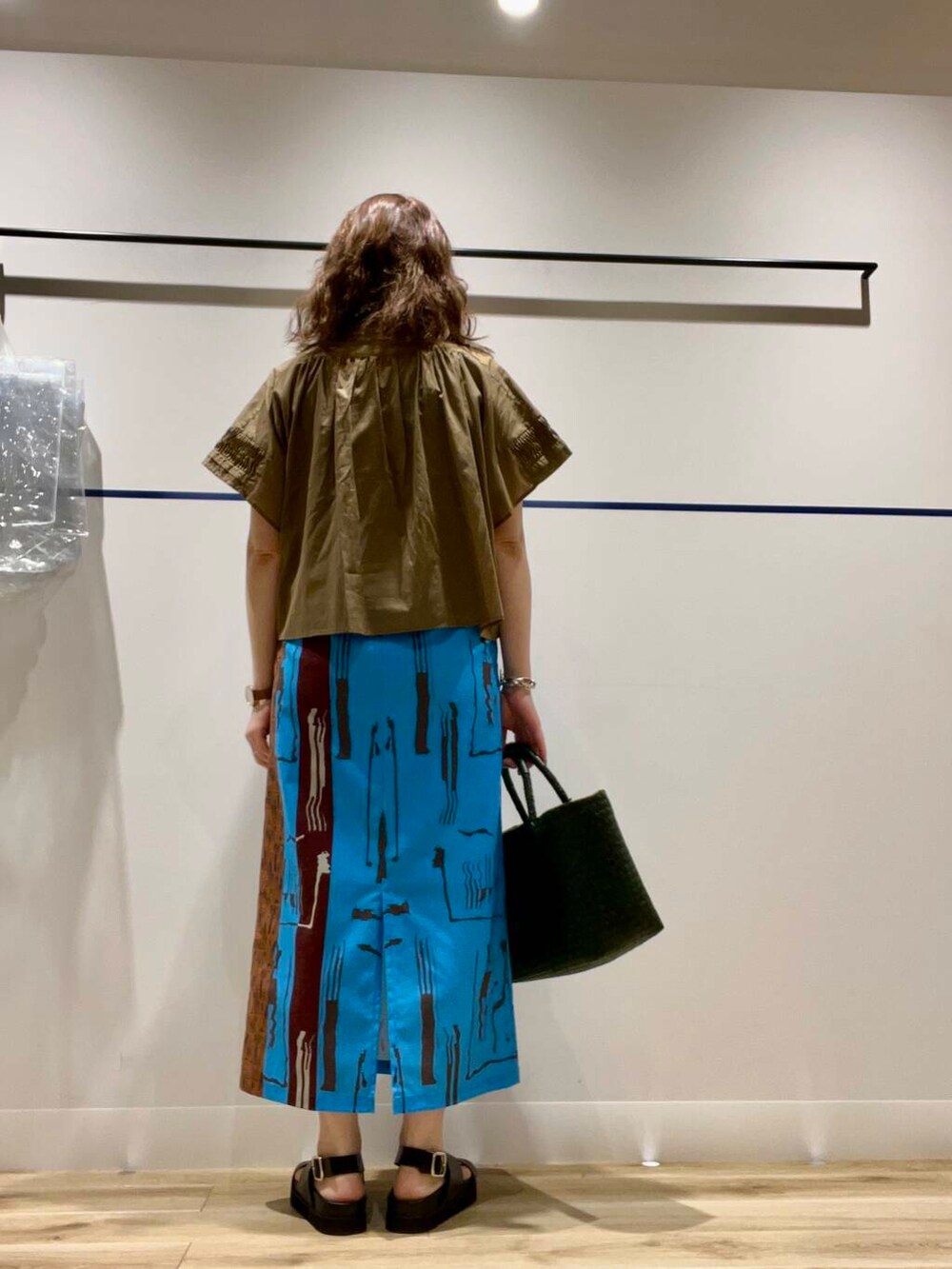 グリーン系のトートバッグ、ブラック系のタンクトップ、ブラック系のサンダルを着用したレディースの夏コーディネートの3枚目の写真