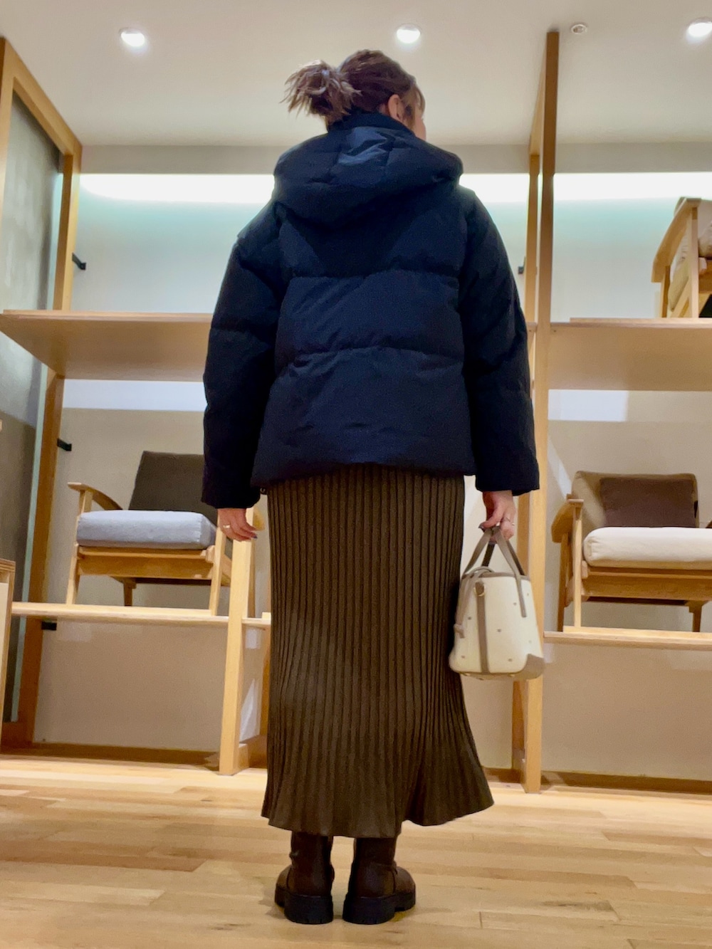 ブラック系のダウンジャケット/コート、ベージュ系のハンドバッグ、ブラウン系のワンピースを着用したレディースの秋コーディネートの4枚目の写真