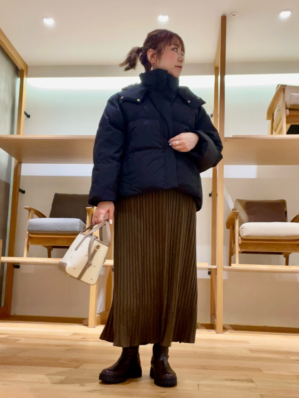 ブラック系のダウンジャケット/コート、ベージュ系のハンドバッグ、ブラウン系のワンピースを着用したレディースの秋コーディネートの2枚目の写真