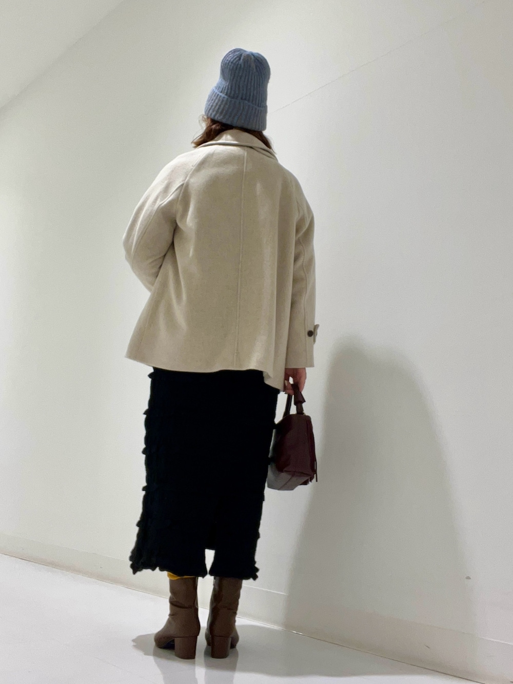 ベージュ系のピーコート、ベージュ系のトップス、ブラウン系のブーツを着用したレディースの冬コーディネートの3枚目の写真