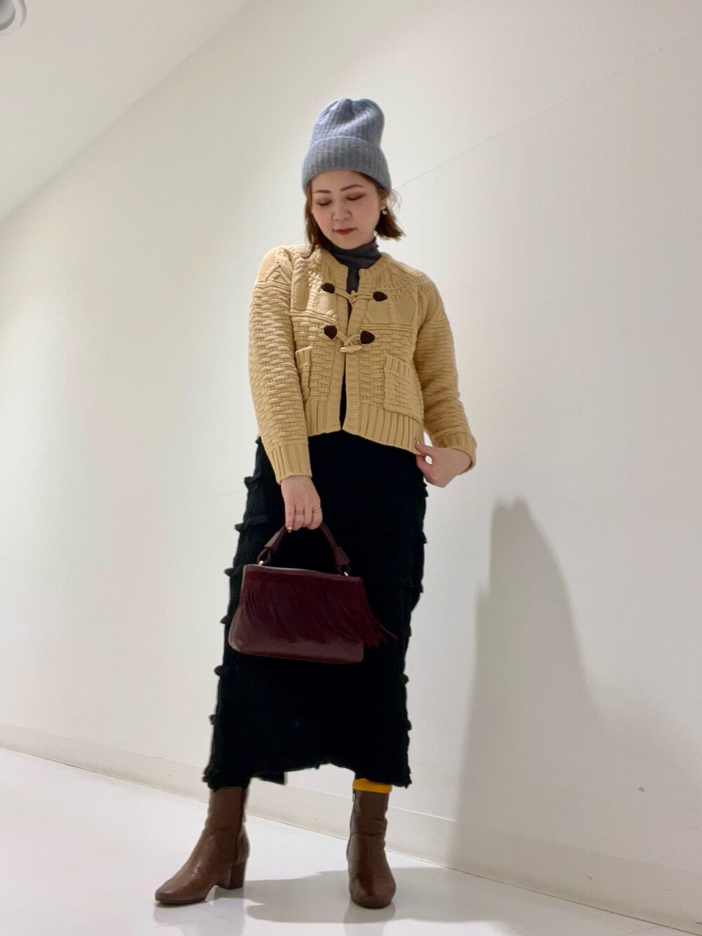 ベージュ系のピーコート、ベージュ系のトップス、ブラウン系のブーツを着用したレディースの冬コーディネートの6枚目の写真