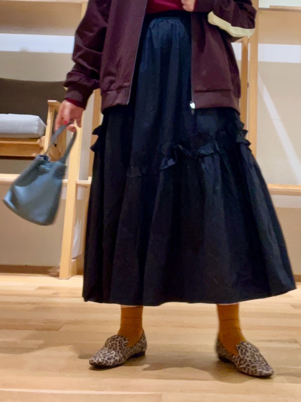 ブルー系のショルダーバッグ、ブラック系のスカート、レッド系のTシャツ/カットソーを着用したレディースの秋コーディネートの4枚目の写真