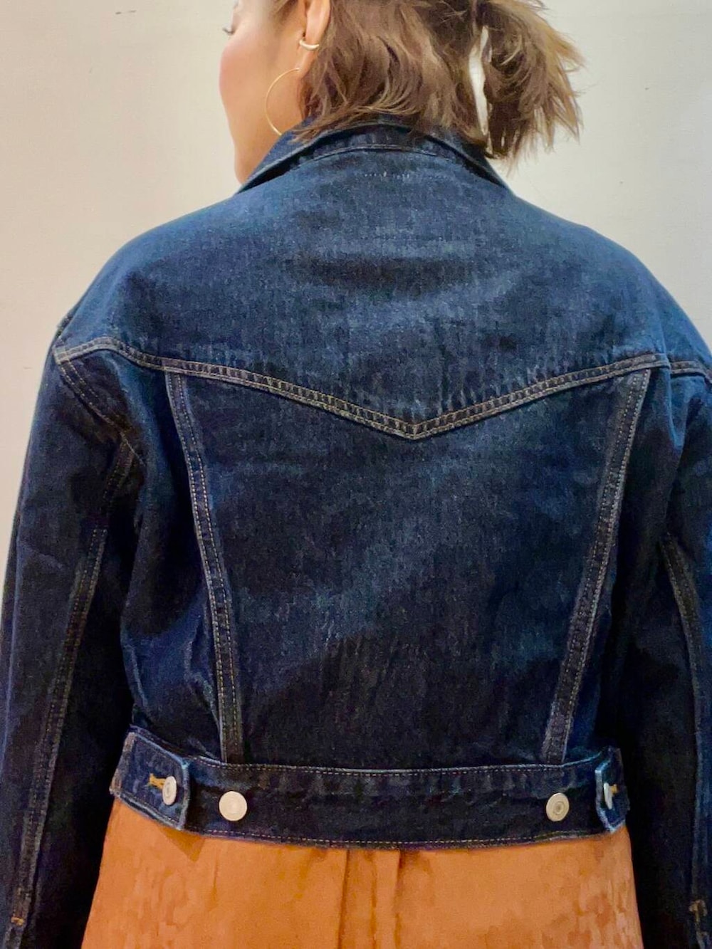 シルバー系のハンドバッグ、ブルー系のデニムジャケット、ホワイト系のスニーカーを着用したレディースの夏コーディネートの5枚目の写真