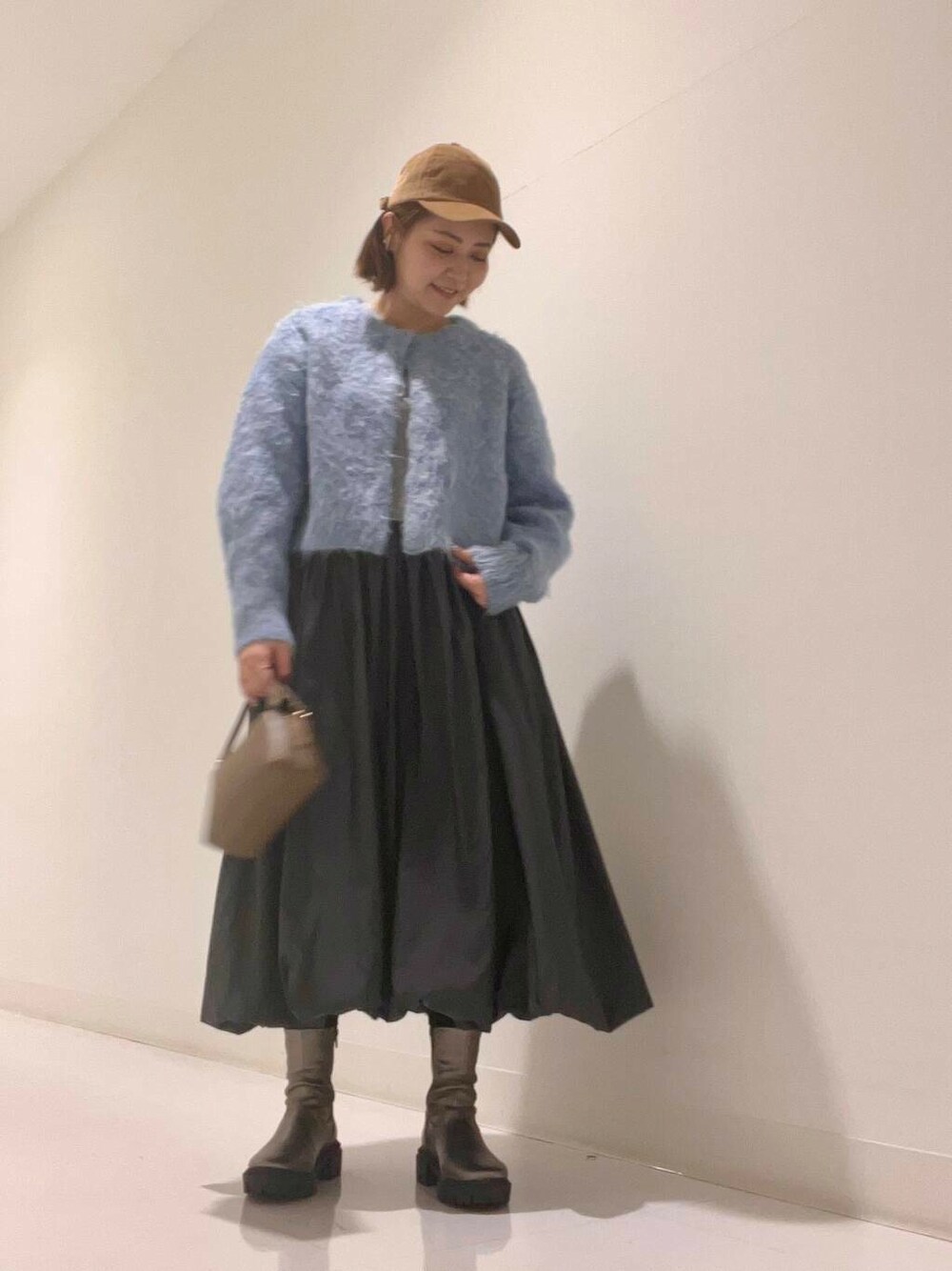 ベージュ系のステンカラーコート、シルバー系のブーツ、グレー系のワンピースを着用したレディースの冬コーディネートの7枚目の写真