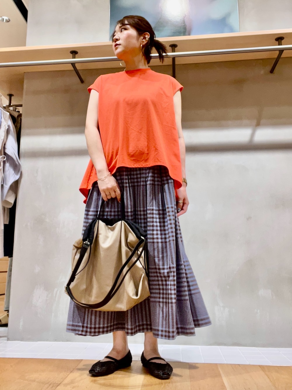 レッド系のTシャツ/カットソー、ブラウン系のスカート、ベージュ系のショルダーバッグを着用したレディースの夏コーディネートの4枚目の写真