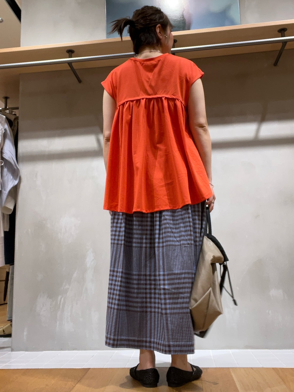 レッド系のTシャツ/カットソー、ブラウン系のスカート、ベージュ系のショルダーバッグを着用したレディースの夏コーディネートの3枚目の写真