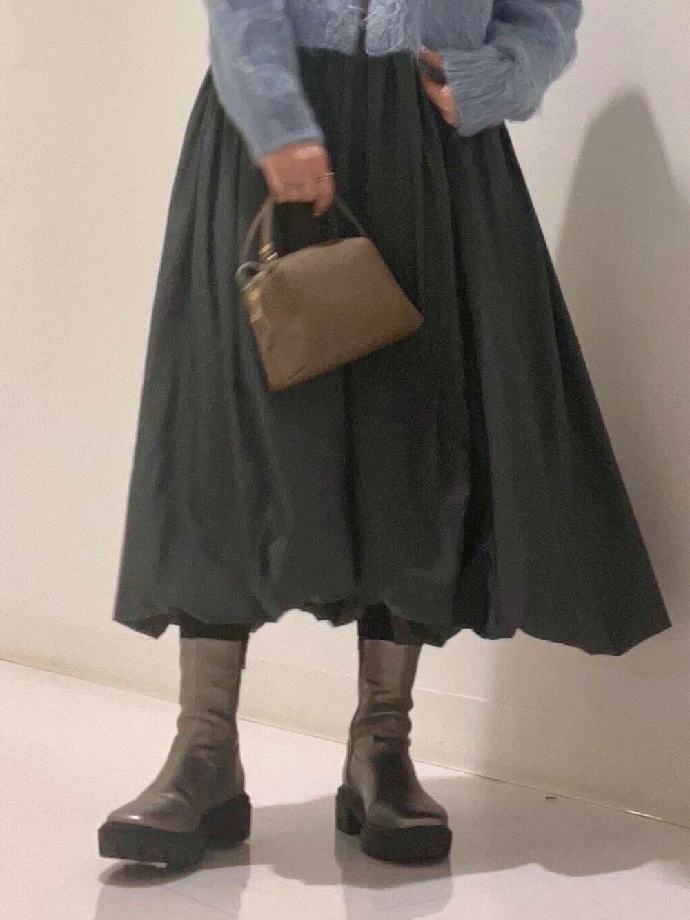 ベージュ系のステンカラーコート、シルバー系のブーツ、グレー系のワンピースを着用したレディースの冬コーディネートの10枚目の写真