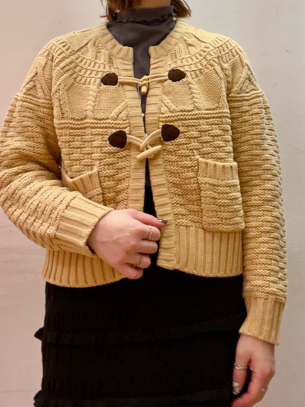 ベージュ系のピーコート、ベージュ系のトップス、ブラウン系のブーツを着用したレディースの冬コーディネートの7枚目の写真