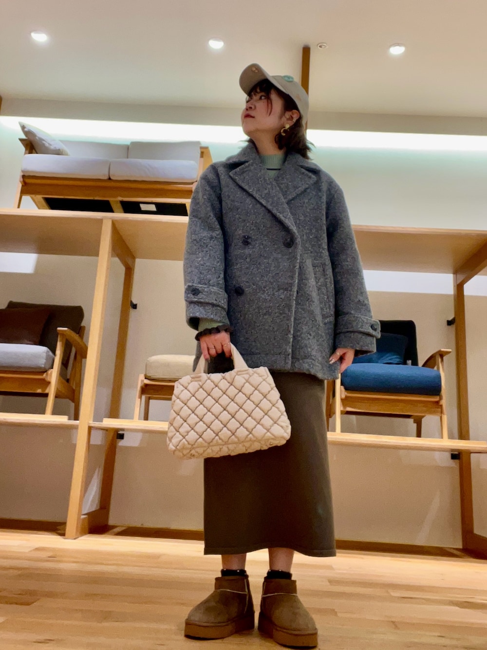 ホワイト系のハンドバッグ、グレー系のその他アウター、グリーン系のニット/セーターを着用したレディースの秋コーディネートの2枚目の写真