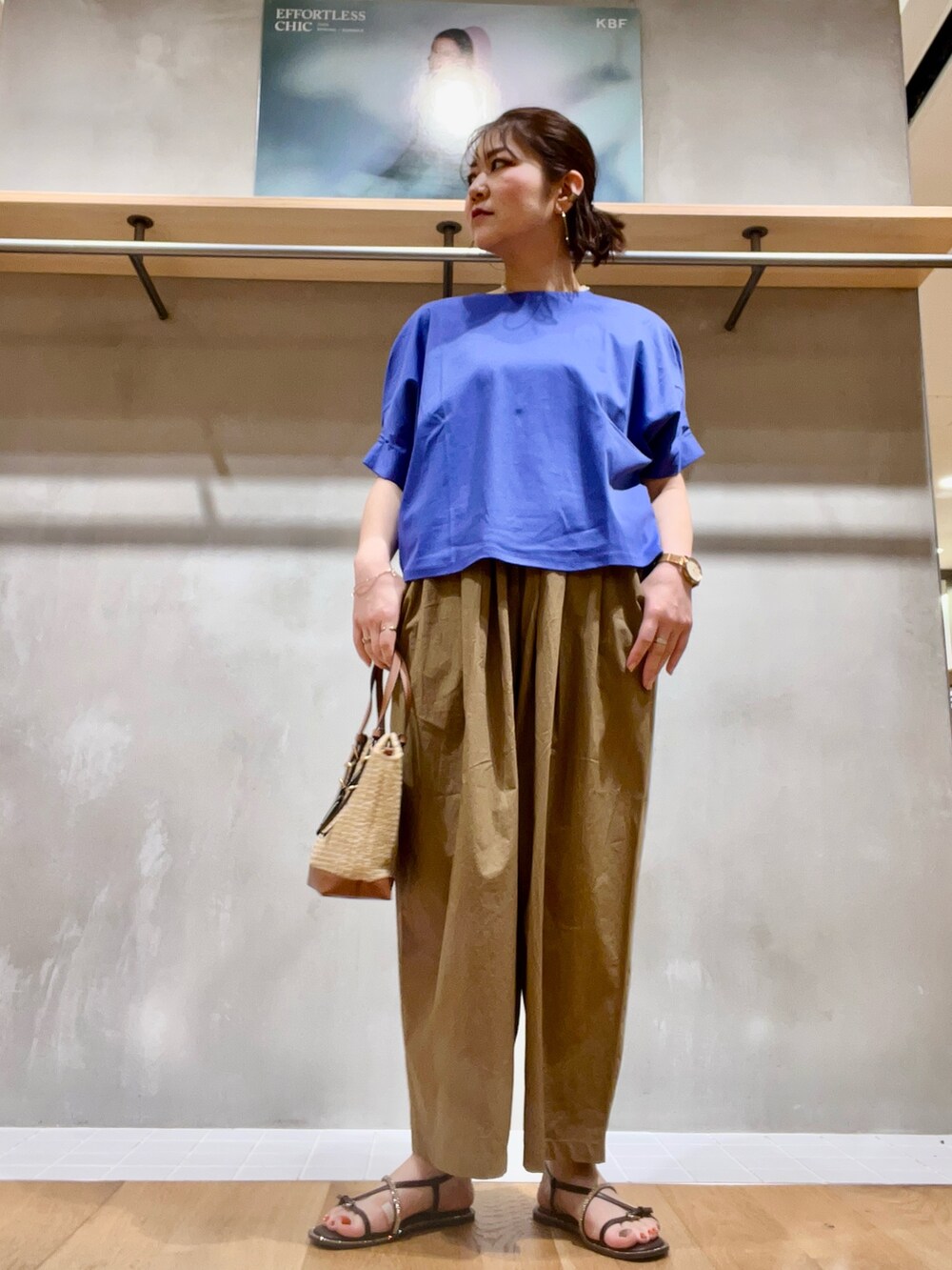 ブルー系のTシャツ/カットソー、ブラウン系のパンツ、ベージュ系のかごバッグを着用したレディースの夏コーディネートの2枚目の写真