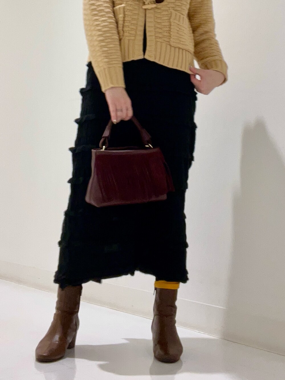 ベージュ系のピーコート、ベージュ系のトップス、ブラウン系のブーツを着用したレディースの冬コーディネートの8枚目の写真