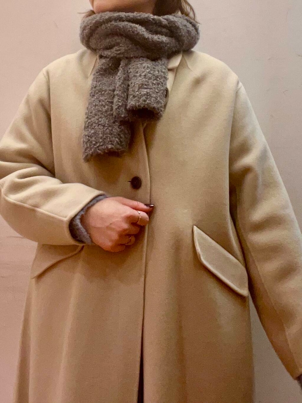 ベージュ系のステンカラーコート、シルバー系のブーツ、グレー系のワンピースを着用したレディースの冬コーディネートの4枚目の写真