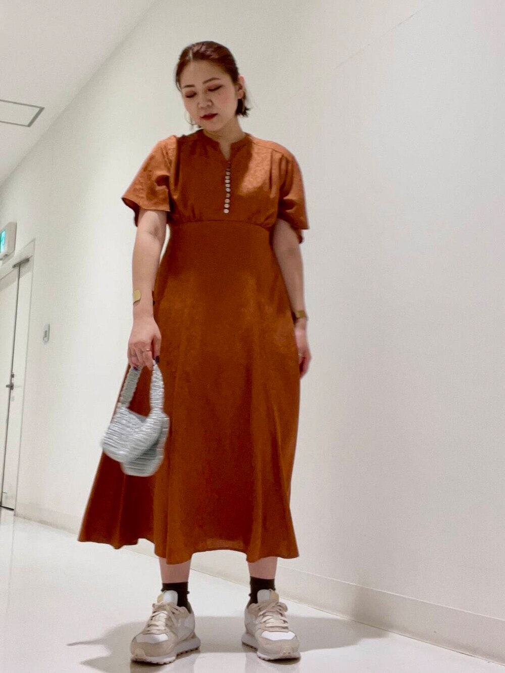 シルバー系のハンドバッグ、ブルー系のデニムジャケット、ホワイト系のスニーカーを着用したレディースの夏コーディネートの6枚目の写真