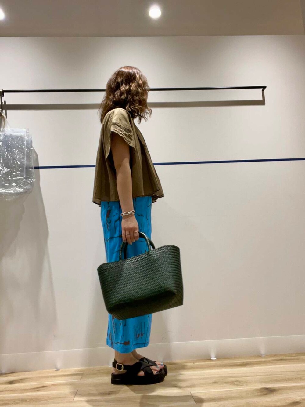 グリーン系のトートバッグ、ブラック系のタンクトップ、ブラック系のサンダルを着用したレディースの夏コーディネートの2枚目の写真