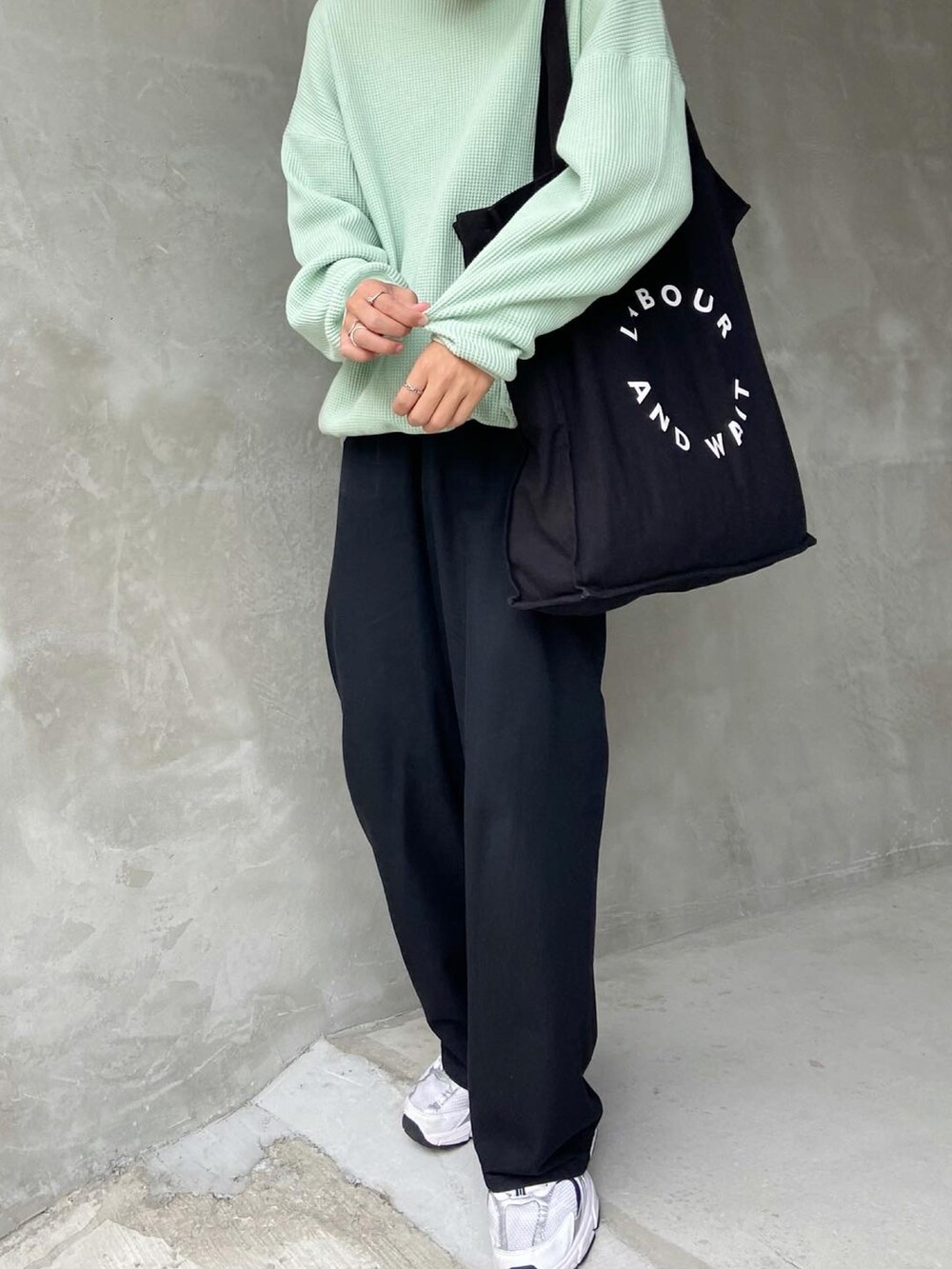 グリーン系のニット/セーター、ブラック系のトートバッグ、ブラック系のデニムパンツを着用したメンズの秋コーディネートの3枚目の写真