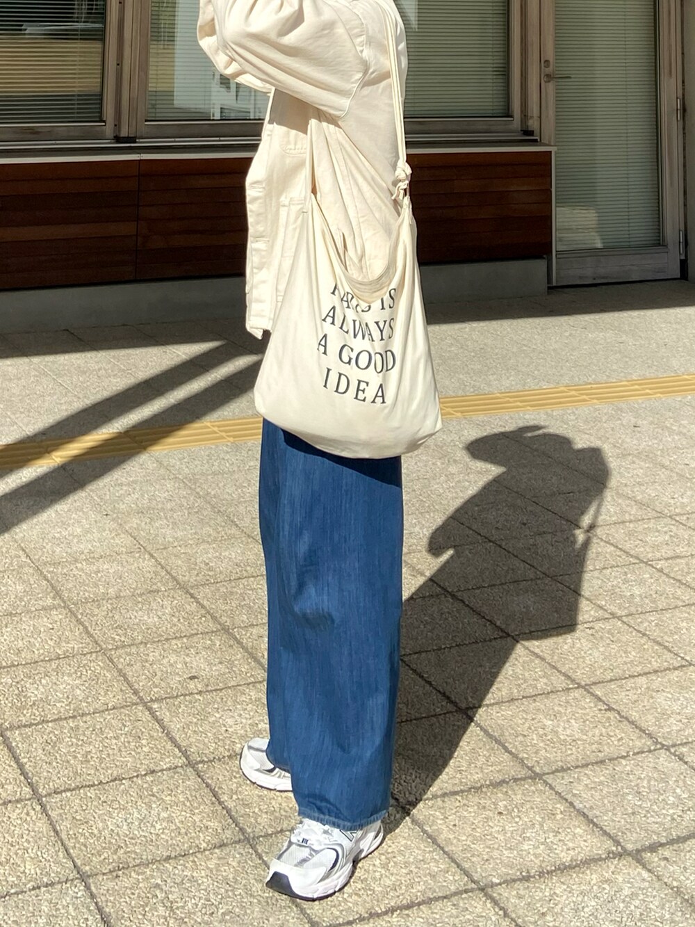 ホワイト系のカバーオール、ベージュ系のショルダーバッグ、ブルー系のデニムパンツを着用したメンズの春コーディネートの2枚目の写真