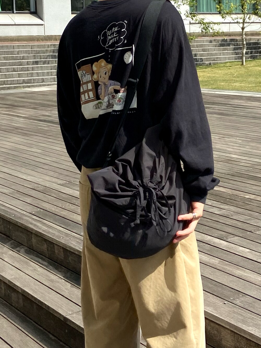 ブラック系のTシャツ/カットソー、ブラック系のショルダーバッグ、ベージュ系のチノパンツを着用したメンズの春コーディネートの3枚目の写真