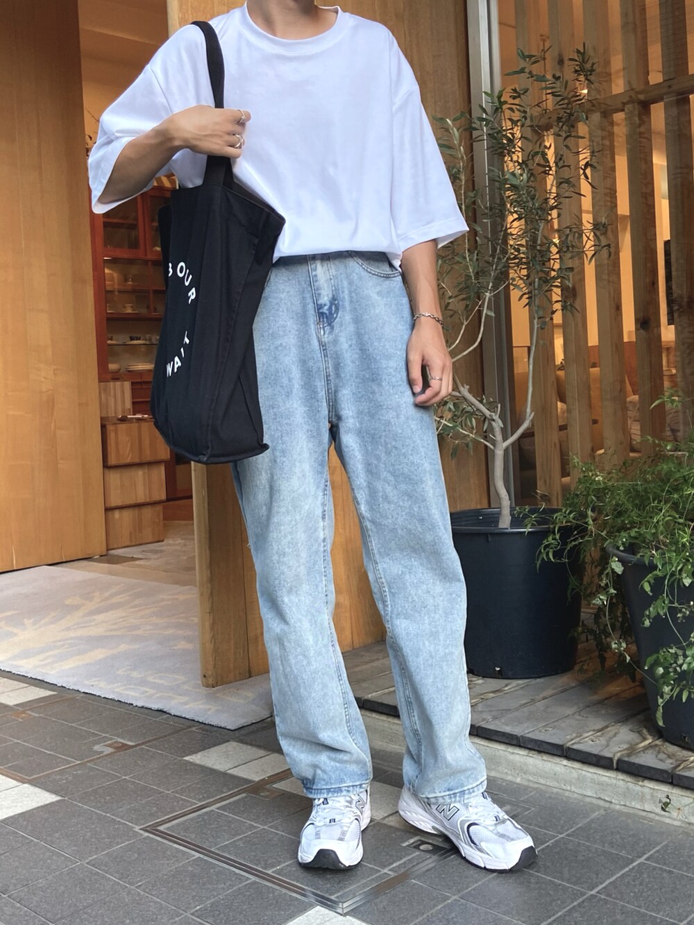 ホワイト系のTシャツ/カットソー、ブラック系のトートバッグ、ブルー系のデニムパンツを着用したメンズの夏コーディネートの3枚目の写真