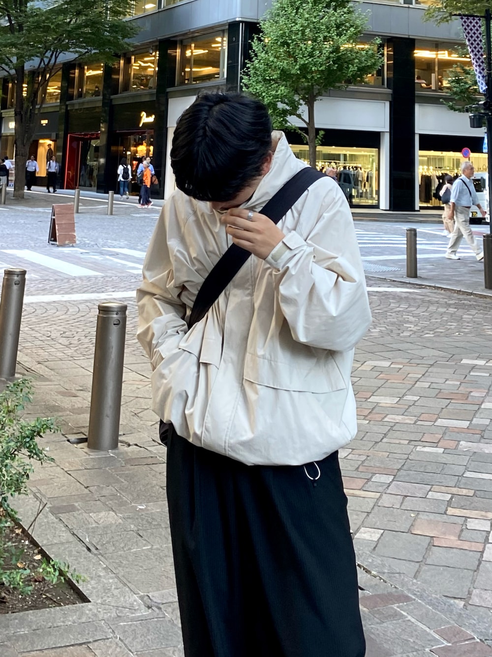 ブラック系のスラックス、ブラック系のスニーカー、ホワイト系のブルゾンを着用したメンズの秋コーディネートの2枚目の写真