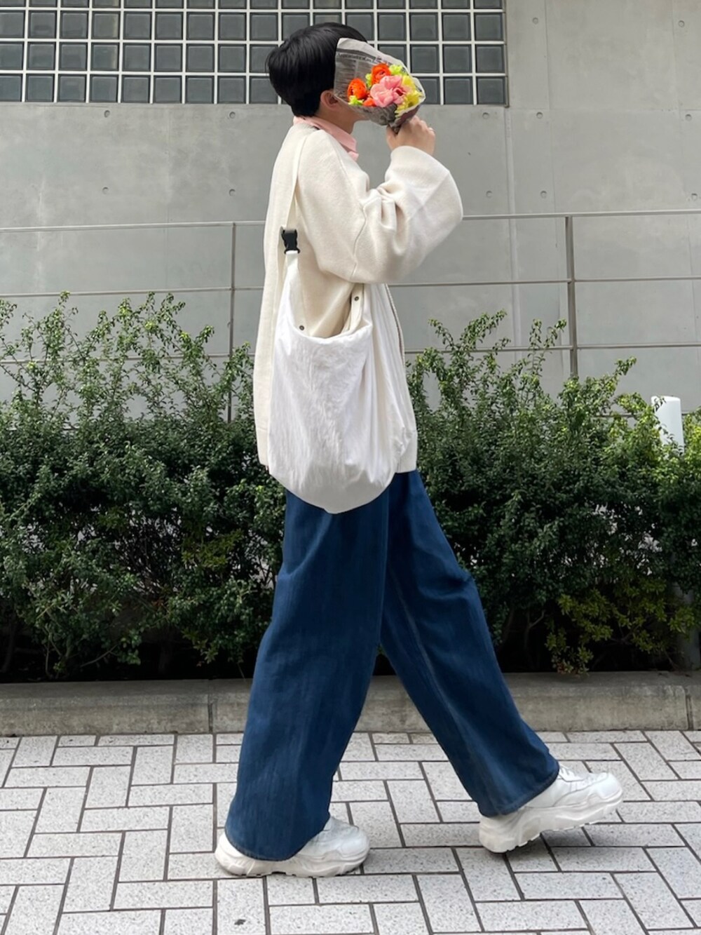 ホワイト系のカーディガン/ボレロ、ホワイト系のショルダーバッグ、ブルー系のデニムパンツを着用したメンズの春コーディネートの2枚目の写真