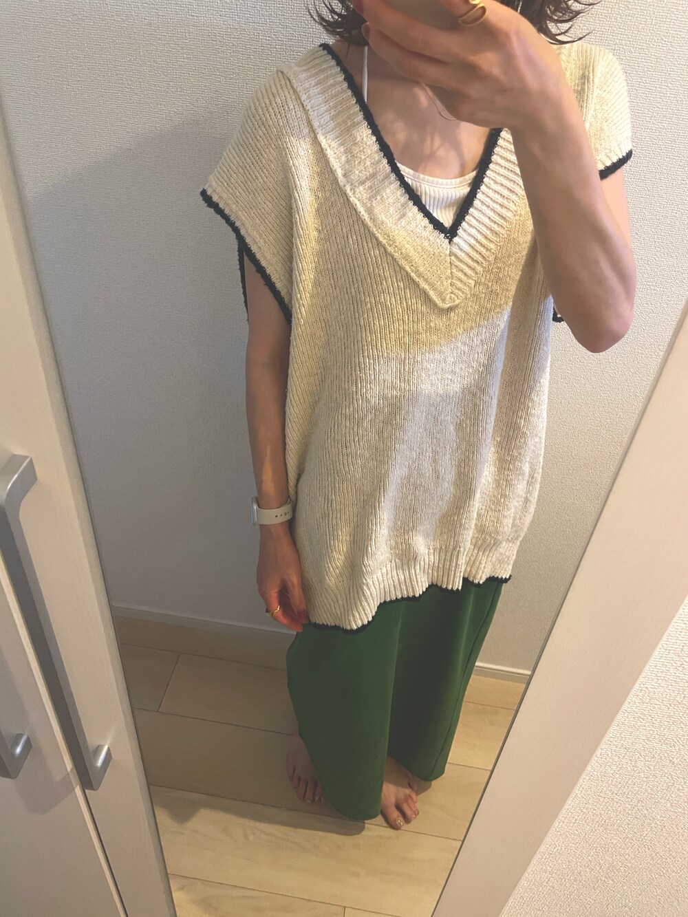 ベージュ系のベスト、グリーン系のスカートを着用したレディースの夏コーディネートの2枚目の写真