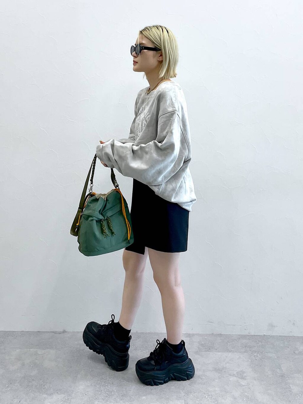 ブラック系のブーツ、ブラック系のスカート、グリーン系のショルダーバッグを着用したレディースの秋コーディネートの6枚目の写真