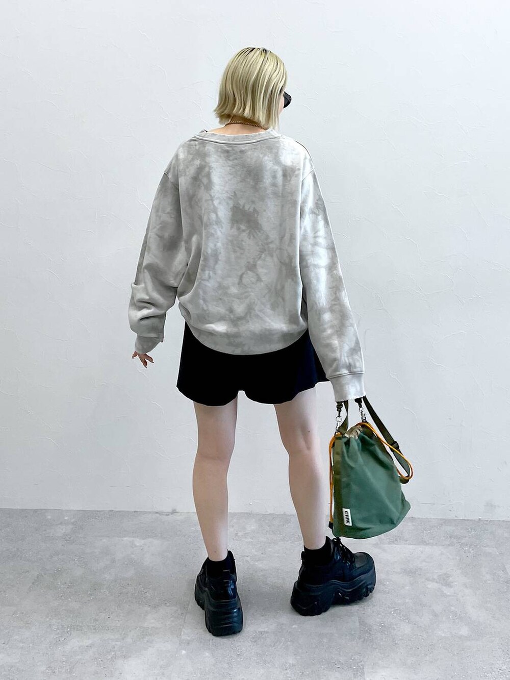 ブラック系のブーツ、ブラック系のスカート、グリーン系のショルダーバッグを着用したレディースの秋コーディネートの8枚目の写真