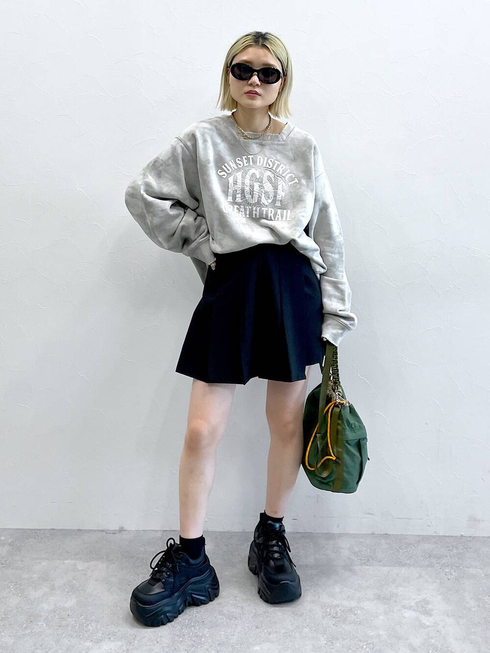 ブラック系のブーツ、ブラック系のスカート、グリーン系のショルダーバッグを着用したレディースの秋コーディネートの5枚目の写真