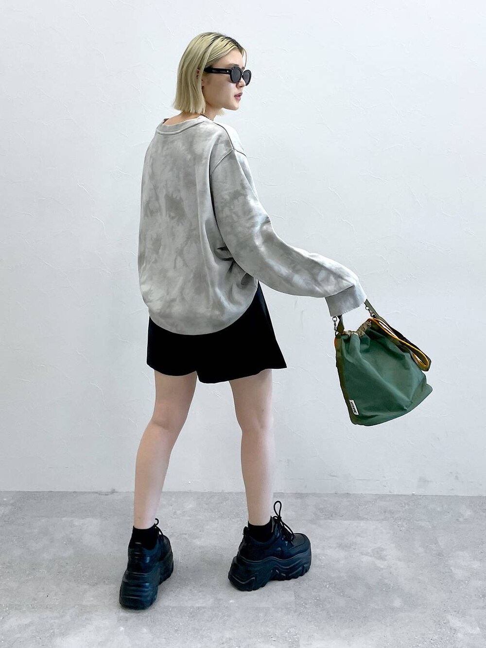 ブラック系のブーツ、ブラック系のスカート、グリーン系のショルダーバッグを着用したレディースの秋コーディネートの9枚目の写真