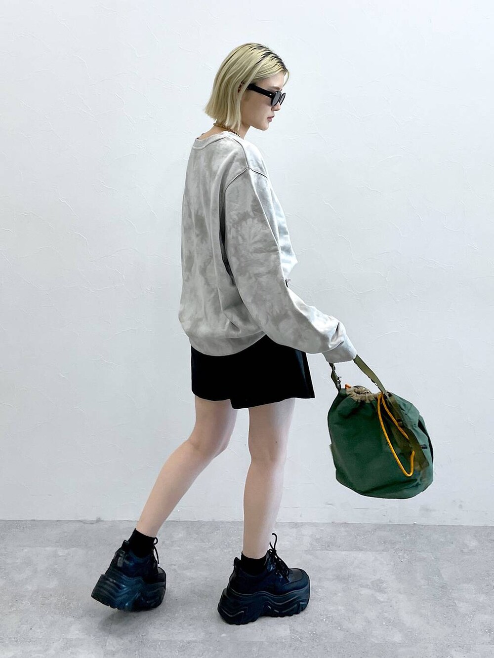 ブラック系のブーツ、ブラック系のスカート、グリーン系のショルダーバッグを着用したレディースの秋コーディネートの7枚目の写真