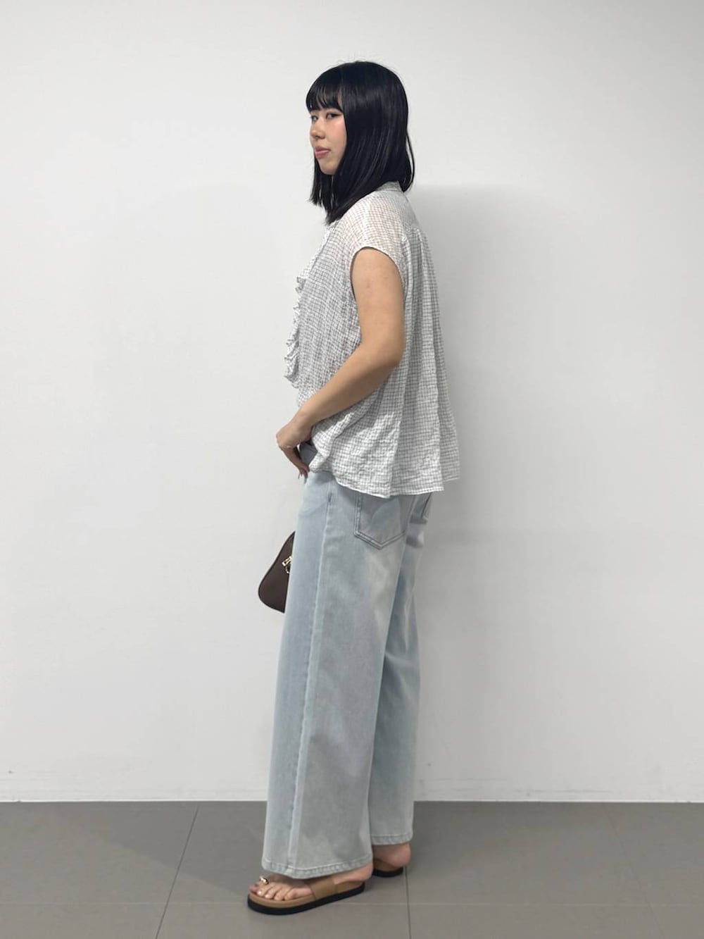 ブラウン系のボストンバッグ、ブルー系のデニムパンツ、ブラウン系のサンダルを着用したレディースの夏コーディネートの2枚目の写真