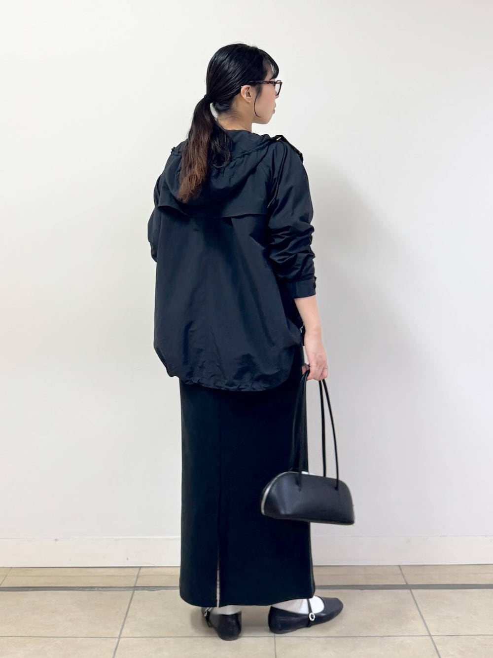 ブラック系のスカート、ブラック系のハンドバッグ、ブラック系のマウンテンパーカーを着用したレディースの春コーディネートの3枚目の写真