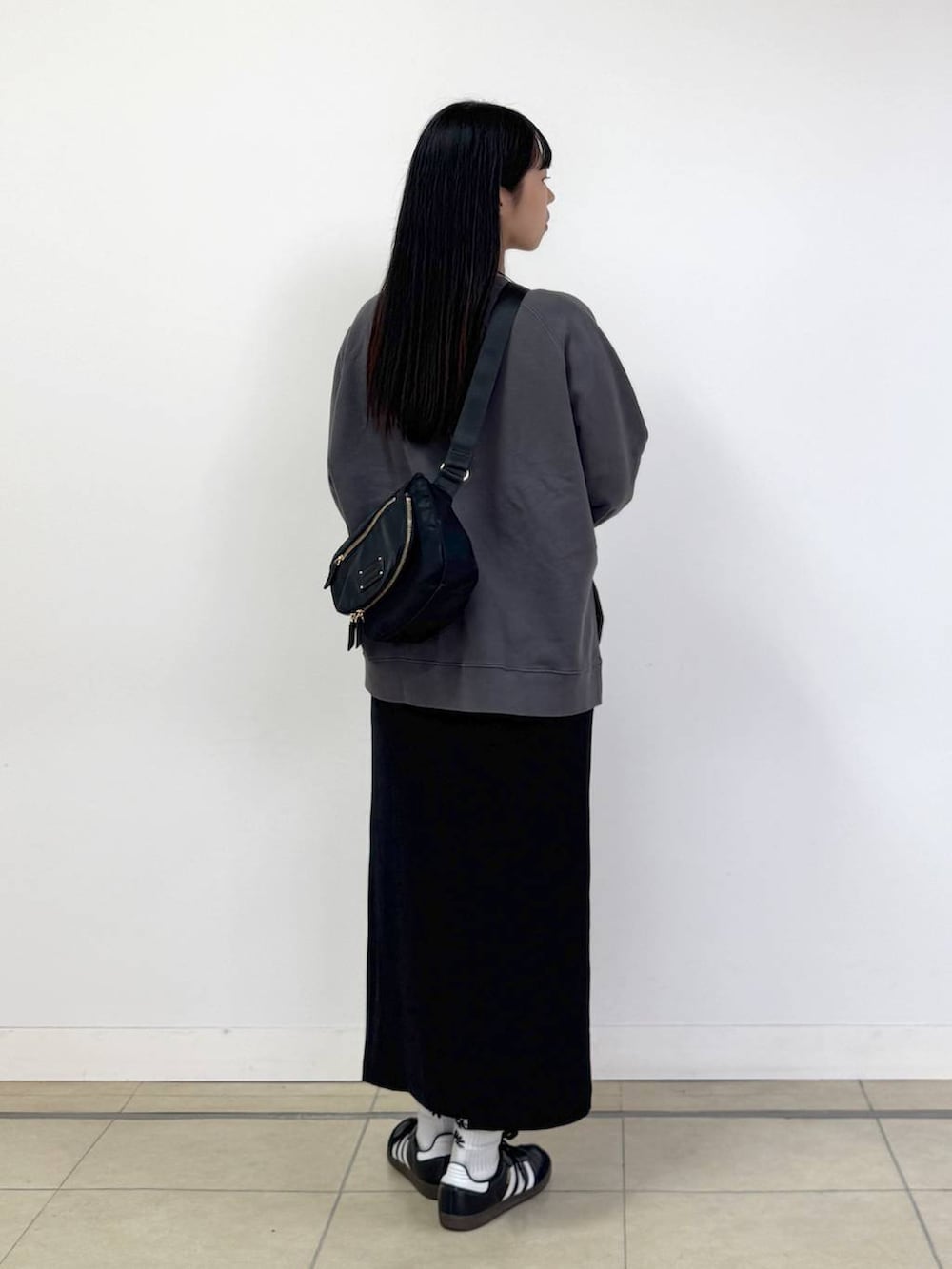 ブラック系のボディバッグ/ウエストポーチ、ブラック系のスカート、ホワイト系のTシャツ/カットソーを着用したレディースの秋コーディネートの3枚目の写真