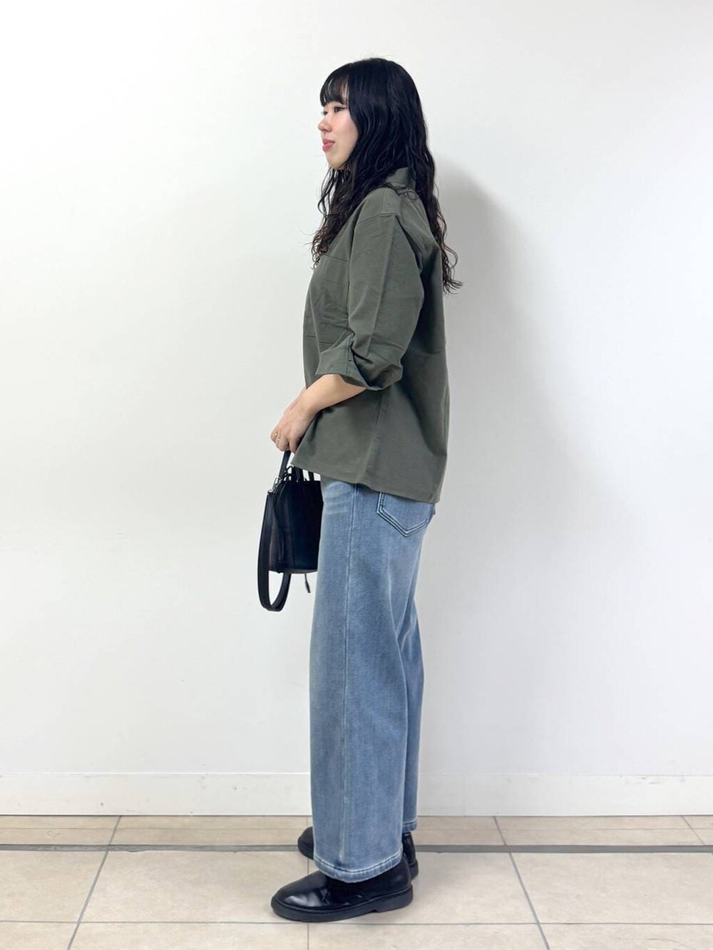 ブルー系のデニムパンツ、ブラック系のブルゾン、グリーン系のシャツ/ブラウスを着用したレディースの冬コーディネートの2枚目の写真