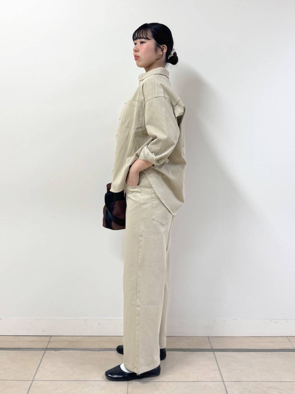 ベージュ系のシャツ/ブラウス、ブラウン系のショルダーバッグ、ベージュ系のデニムパンツを着用したレディースの冬コーディネートの2枚目の写真