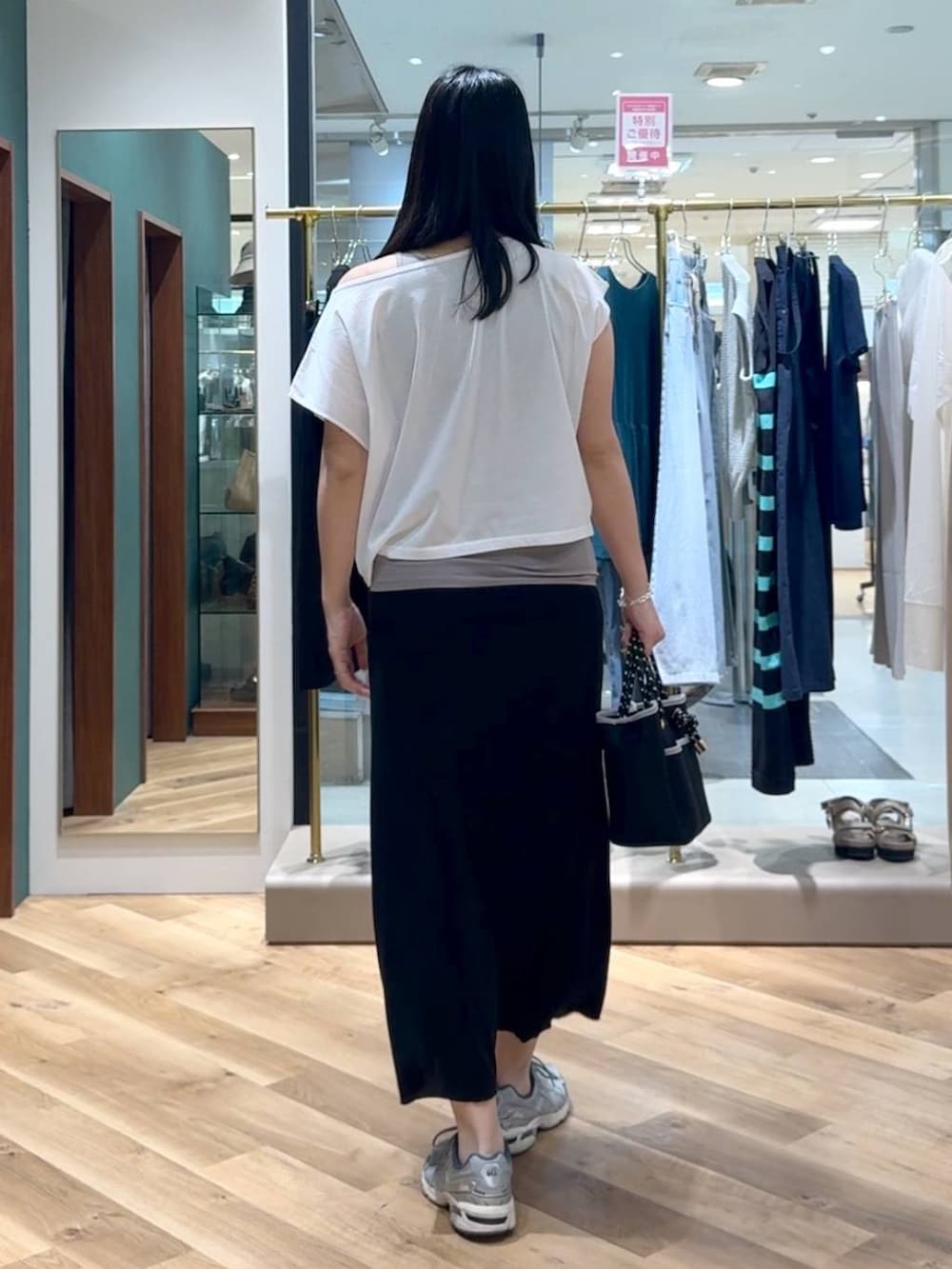 ブラック系のトートバッグ、ブラック系のスカート、ホワイト系のTシャツ/カットソーを着用したレディースの春コーディネートの3枚目の写真