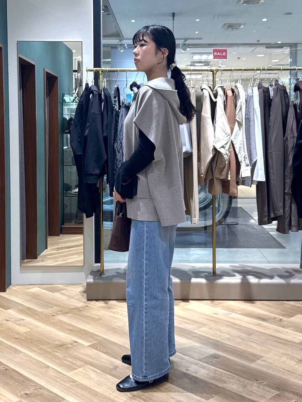 ブルー系のデニムパンツ、グレー系のベスト、ブラウン系のハンドバッグを着用したレディースの冬コーディネートの2枚目の写真