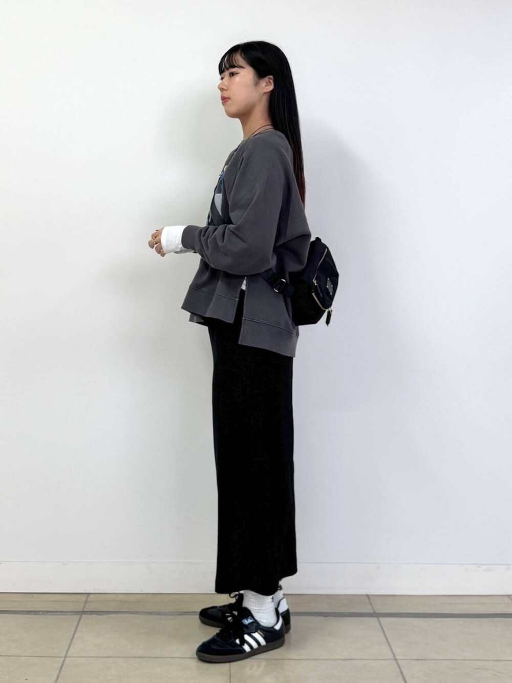 ブラック系のボディバッグ/ウエストポーチ、ブラック系のスカート、ホワイト系のTシャツ/カットソーを着用したレディースの秋コーディネートの2枚目の写真