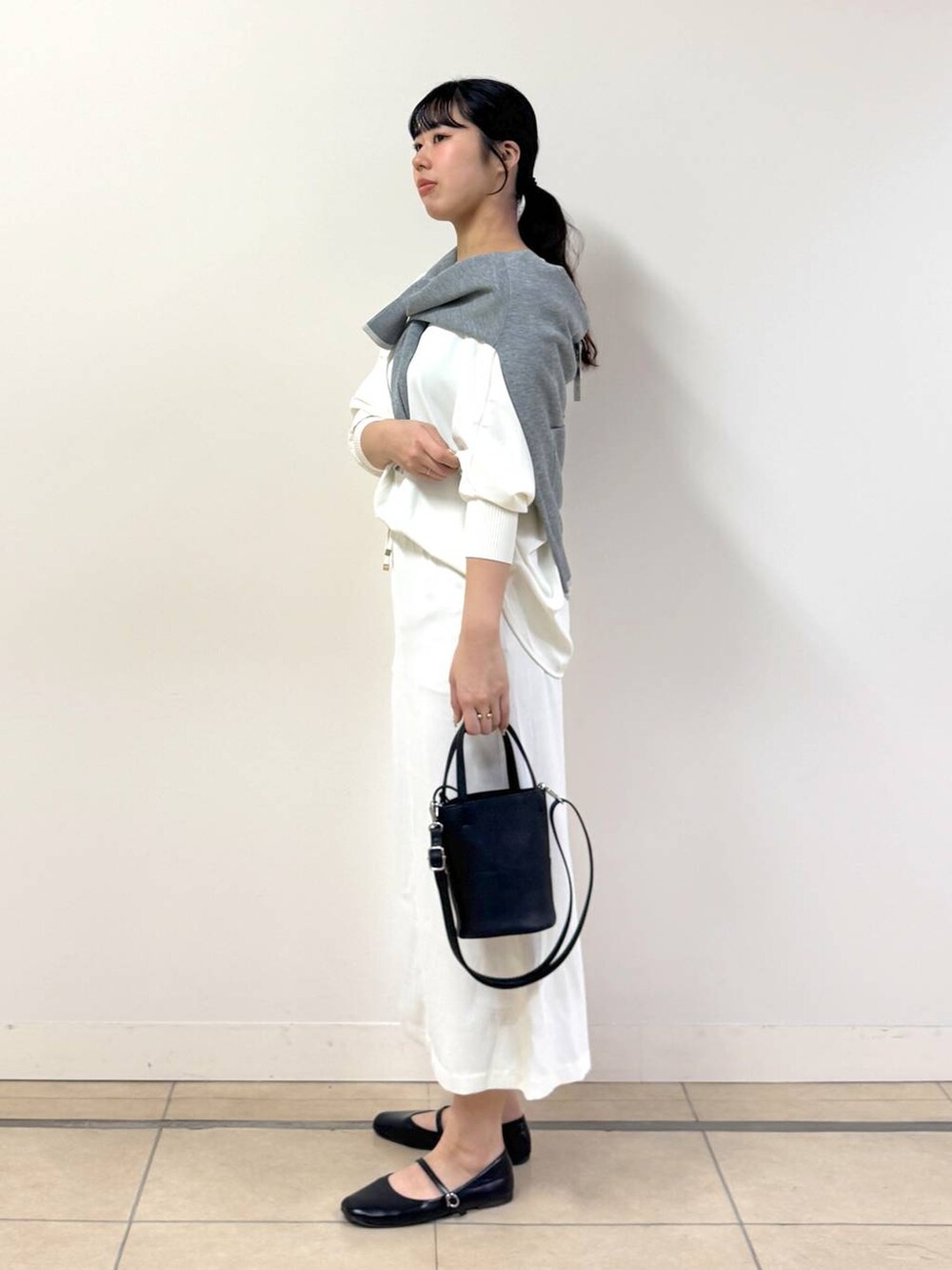 ホワイト系のスカート、ホワイト系のTシャツ/カットソー、グレー系のカーディガン/ボレロを着用したレディースの冬コーディネートの2枚目の写真