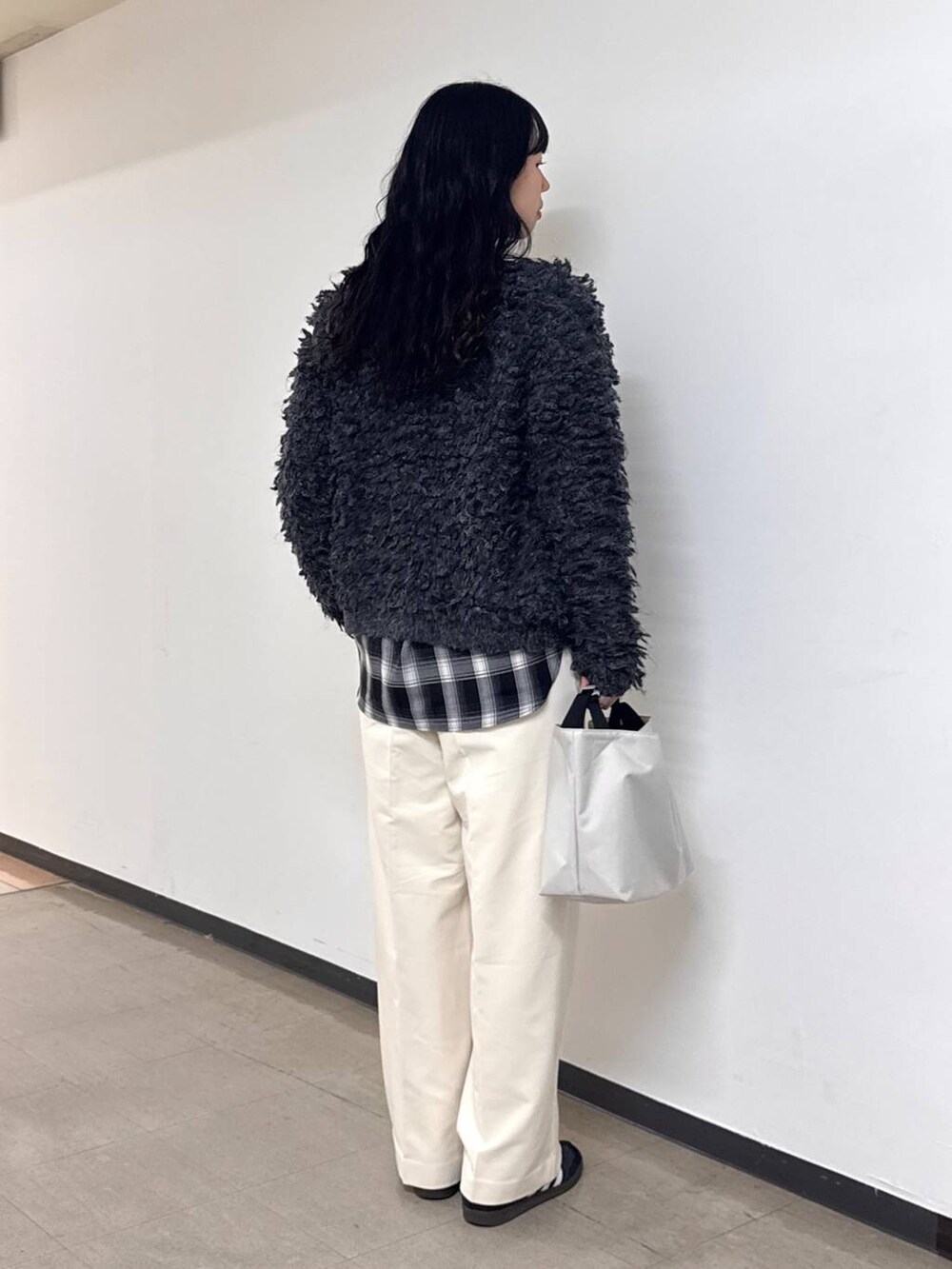 ホワイト系のトートバッグ、ホワイト系のスラックス、グレー系のカーディガン/ボレロを着用したレディースの冬コーディネートの3枚目の写真