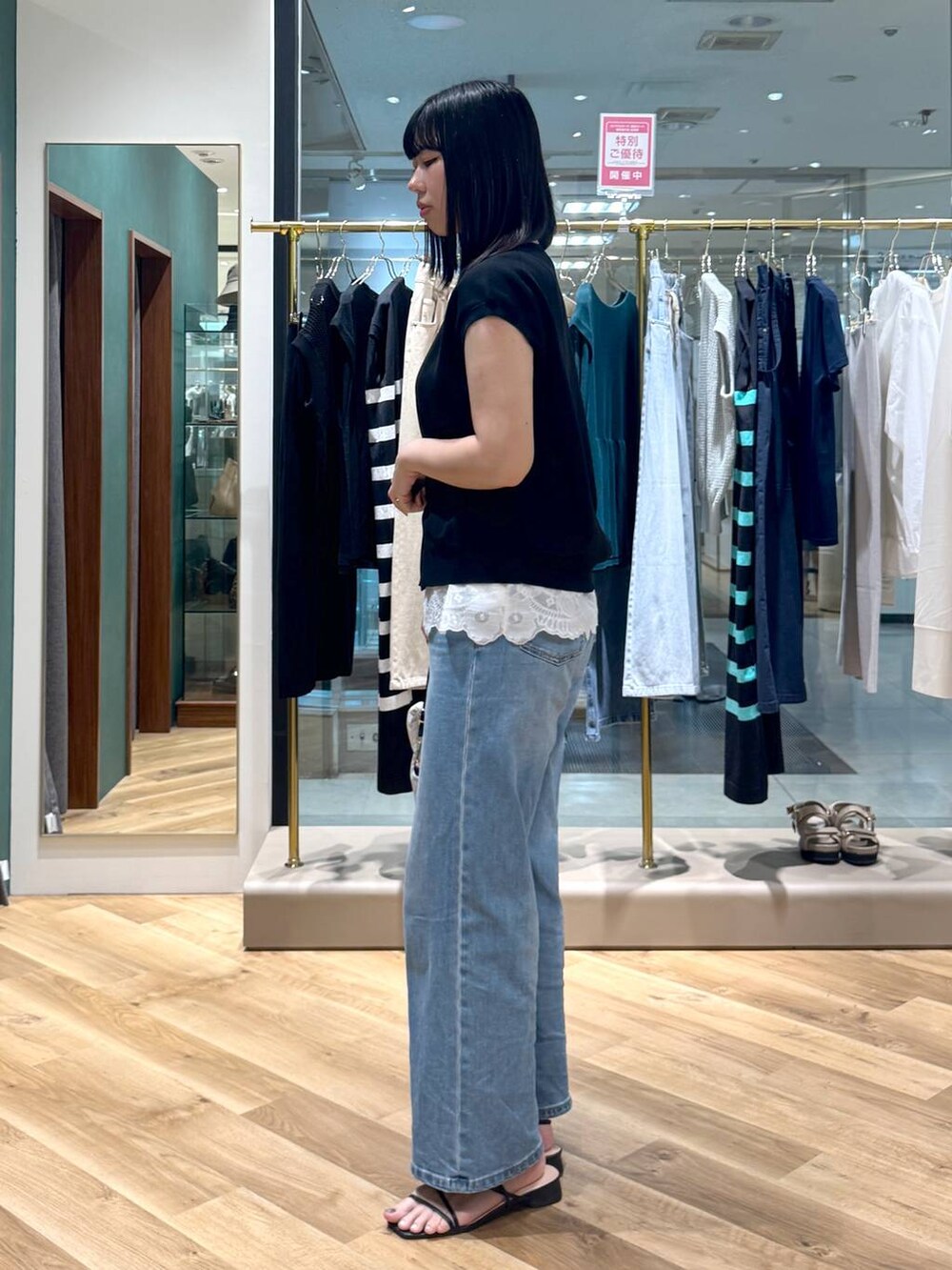 ブルー系のデニムパンツ、ホワイト系のシャツ/ブラウス、ブラック系のニット/セーターを着用したレディースの夏コーディネートの2枚目の写真