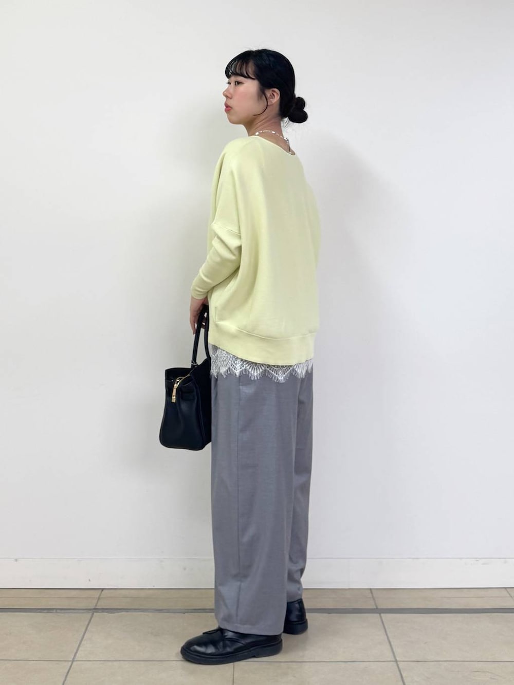 イエロー系のニット/セーター、ブラック系のトートバッグ、グレー系のその他パンツを着用したレディースの冬コーディネートの2枚目の写真