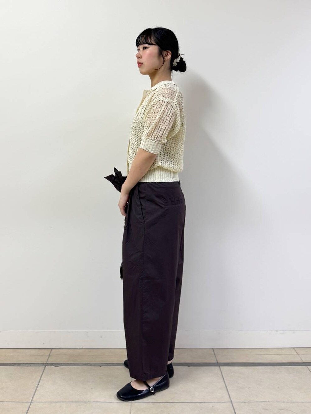 ブラウン系のその他パンツ、ベージュ系のタンクトップ、ホワイト系のニット/セーターを着用したレディースの春コーディネートの2枚目の写真