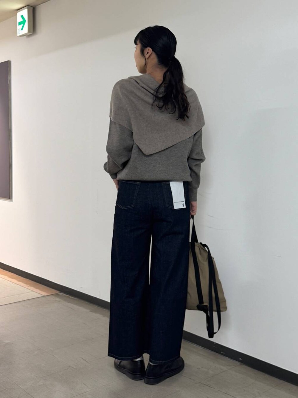 ブルー系のデニムパンツ、ブラウン系のバックパック/リュック、グレー系のニット/セーターを着用したレディースの秋コーディネートの3枚目の写真