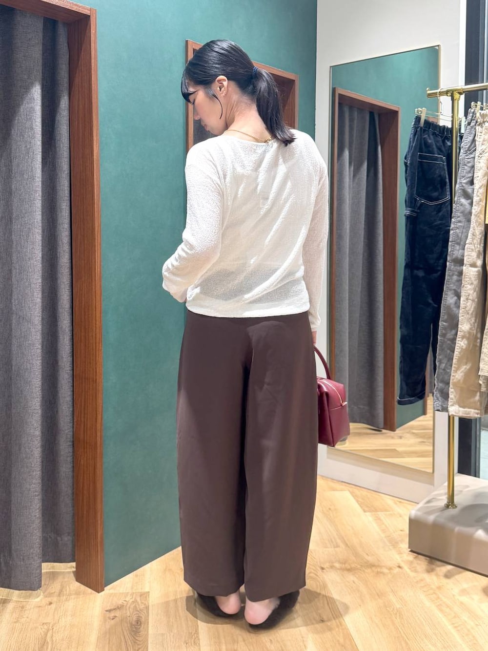 ブラウン系のその他シューズ、レッド系のボストンバッグ、ブラウン系のスラックスを着用したレディースの夏コーディネートの3枚目の写真